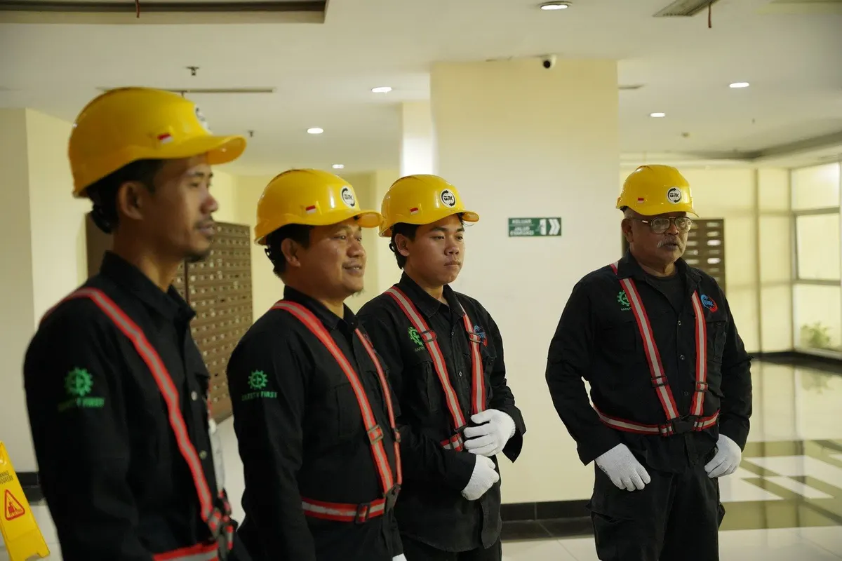 Tim teknisi lift GMK dengan alat pelindung diri lengkap